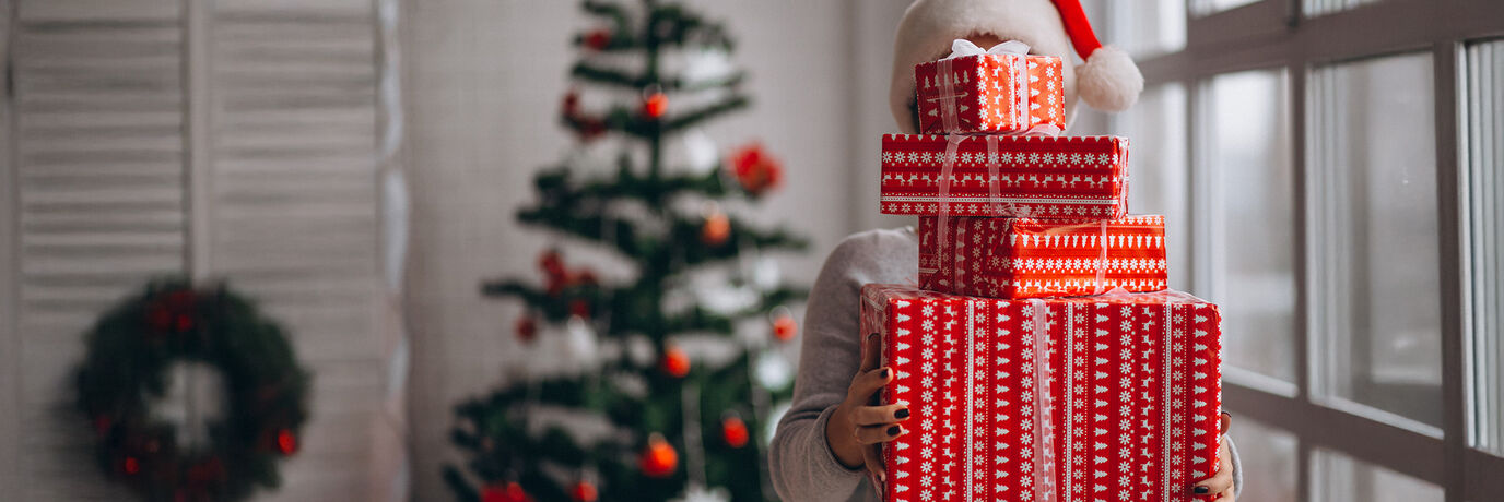 Frau mit 4 Geschenken und Weihnachtsbaum