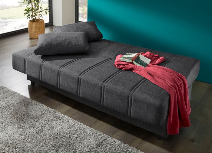 Frei im Raum aufstellbares Schlafsofa mit Dekokissen und Bettkasten 